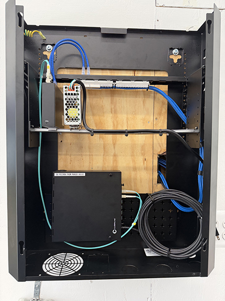 A network rack setup displays a switch and two patch panels with numbered ports, all connected by neatly bundled Ethernet cables routed through cable management bars, illustrating a structured and professional cabling system.