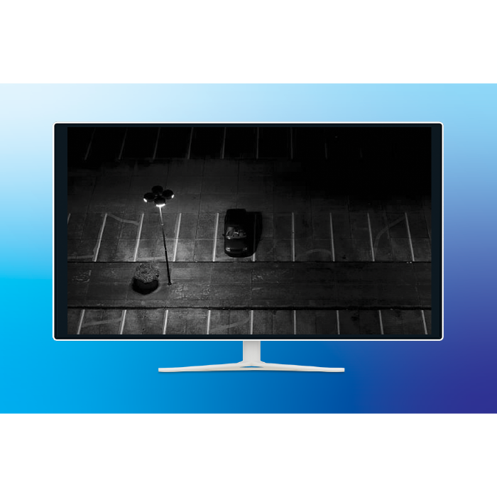 A monitor displaying a nighttime camera view of a parking lot.