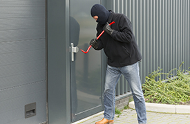 A would-be thief attempting to break into a door with a crowbar.